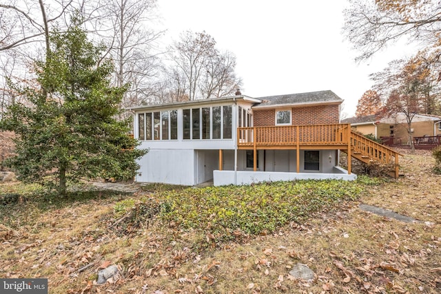 rear view of house featuring a sunroom and a wooden deck