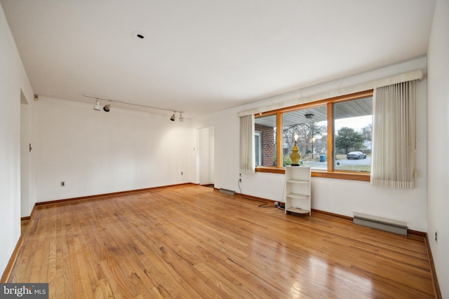 unfurnished room with baseboard heating, light hardwood / wood-style flooring, and rail lighting