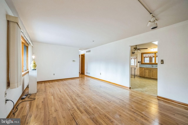 spare room featuring track lighting and light hardwood / wood-style flooring