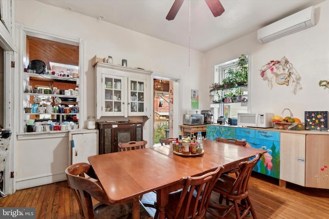 dining area featuring ceiling fan, light hardwood / wood-style floors, and a wall unit AC