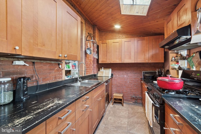 kitchen featuring dark stone counters, black range with gas stovetop, sink, vaulted ceiling with skylight, and wood ceiling