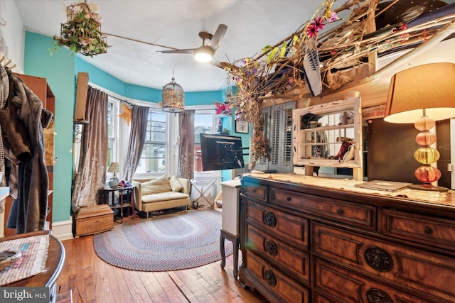 sitting room with ceiling fan and wood-type flooring