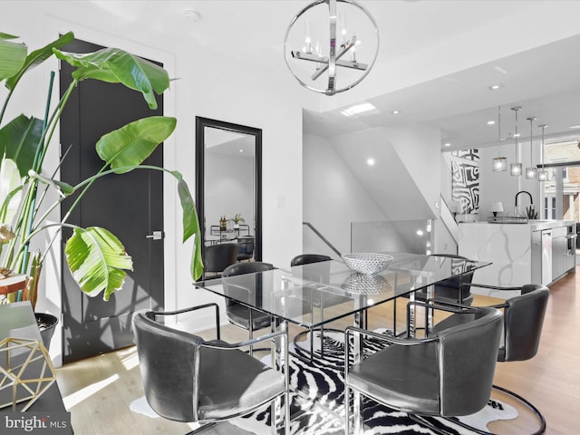 dining space featuring a notable chandelier, light wood-type flooring, and sink