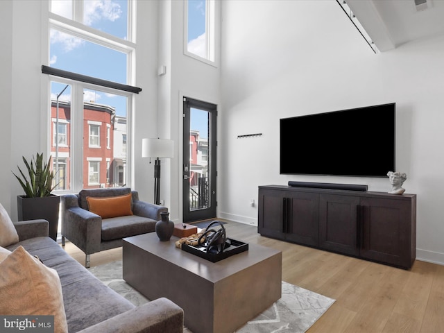 living room featuring a towering ceiling and light hardwood / wood-style floors