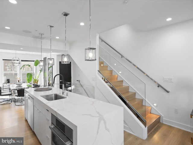 kitchen with white cabinets, a large island, light wood-type flooring, and sink