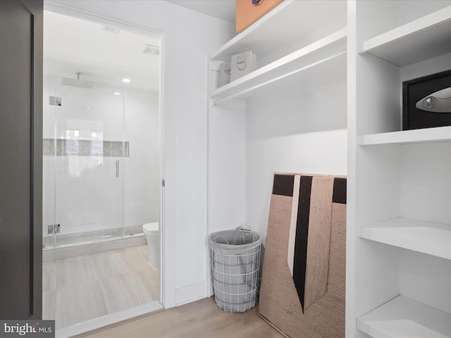 bathroom with hardwood / wood-style flooring, toilet, and an enclosed shower