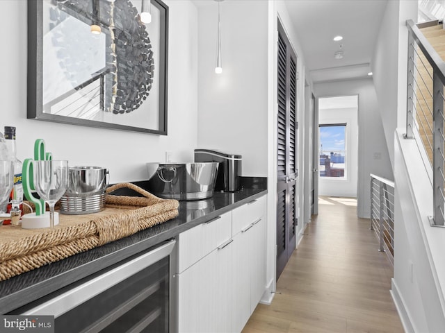 bar with white cabinets, light hardwood / wood-style floors, and beverage cooler