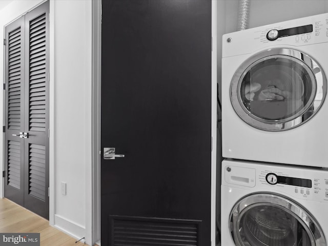 laundry area with hardwood / wood-style floors and stacked washing maching and dryer