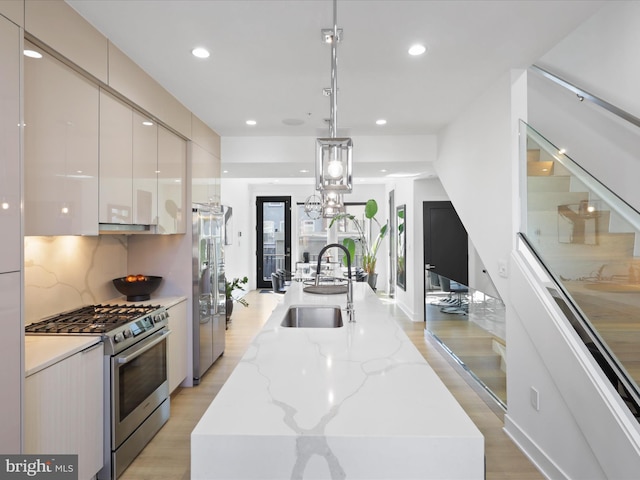 kitchen featuring stainless steel appliances, sink, white cabinetry, a kitchen island, and hanging light fixtures