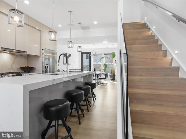 kitchen featuring light hardwood / wood-style floors, white cabinetry, hanging light fixtures, and stainless steel refrigerator with ice dispenser