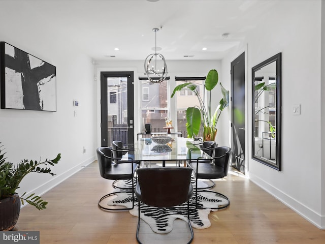 dining space with light wood-type flooring and a notable chandelier