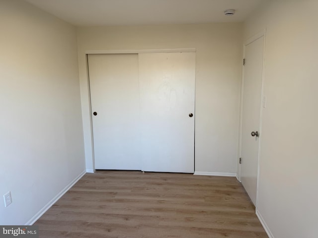 unfurnished bedroom with a closet and light hardwood / wood-style floors