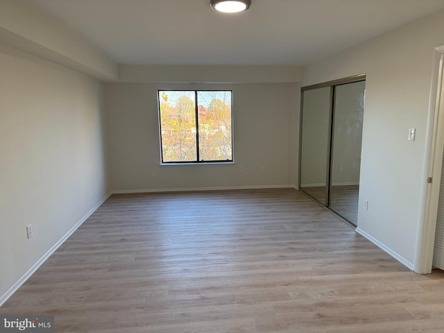 unfurnished bedroom featuring light wood-type flooring and a closet