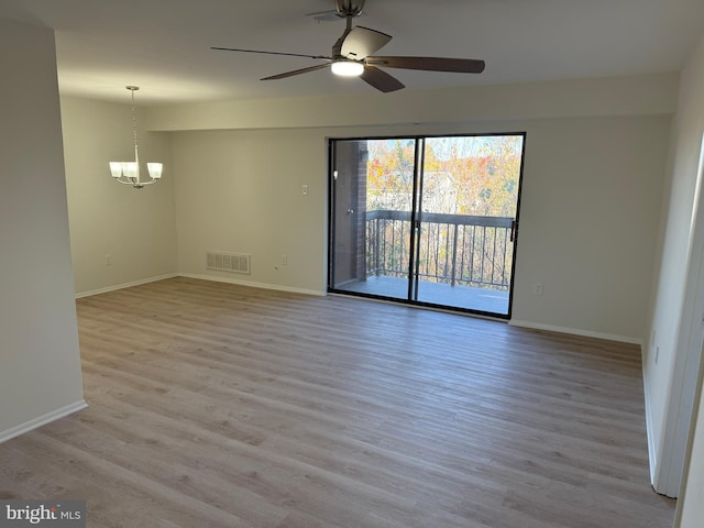 spare room featuring ceiling fan with notable chandelier and light hardwood / wood-style floors