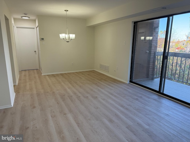 unfurnished room featuring light wood-type flooring and a chandelier