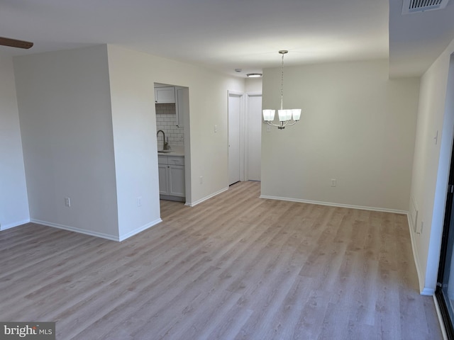 interior space with light hardwood / wood-style floors, an inviting chandelier, and sink