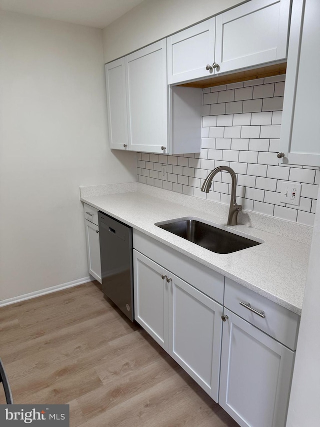 kitchen featuring decorative backsplash, light wood-type flooring, sink, dishwasher, and white cabinetry