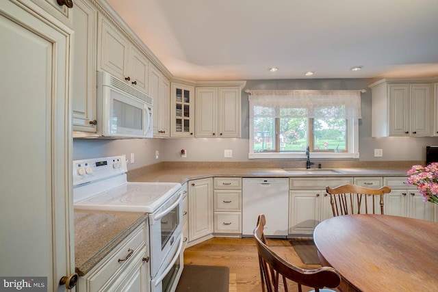 kitchen with cream cabinets, white appliances, light hardwood / wood-style flooring, and sink