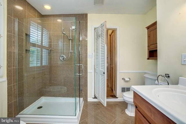 bathroom featuring tile patterned flooring, vanity, toilet, and a shower with shower door