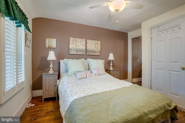 bedroom with a textured ceiling, ceiling fan, dark wood-type flooring, a closet, and lofted ceiling