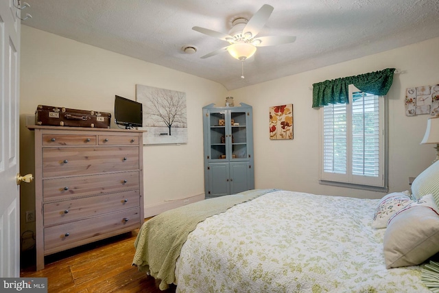 bedroom with ceiling fan, wood-type flooring, and a textured ceiling