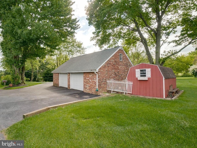 exterior space with a yard, a garage, and a storage unit