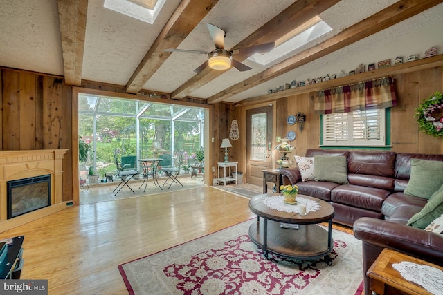 living room featuring wood-type flooring, lofted ceiling with beams, ceiling fan, and wooden walls