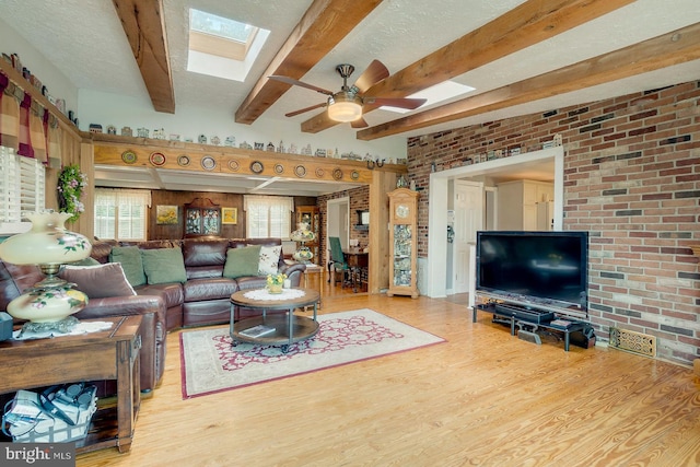 living room featuring brick wall, wood-type flooring, a textured ceiling, and beam ceiling