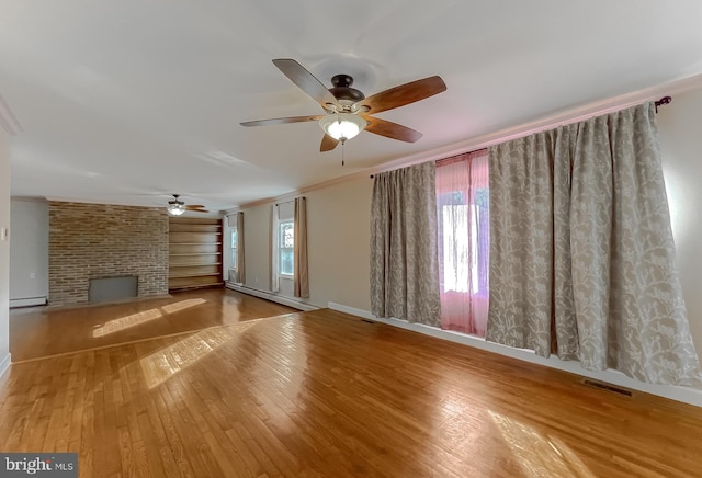 unfurnished living room with crown molding, ceiling fan, a fireplace, a baseboard radiator, and wood-type flooring