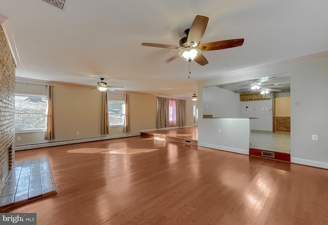 unfurnished living room with hardwood / wood-style floors, ornamental molding, baseboard heating, and a healthy amount of sunlight