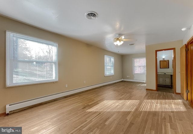 interior space featuring ensuite bathroom, ceiling fan, a baseboard heating unit, and light wood-type flooring