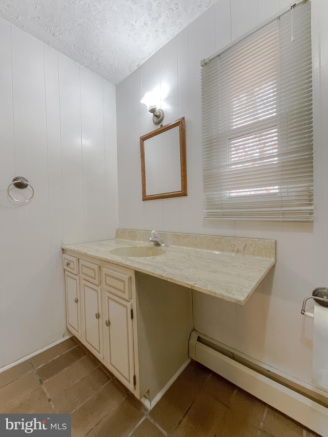 bathroom with vanity, a textured ceiling, and a baseboard heating unit