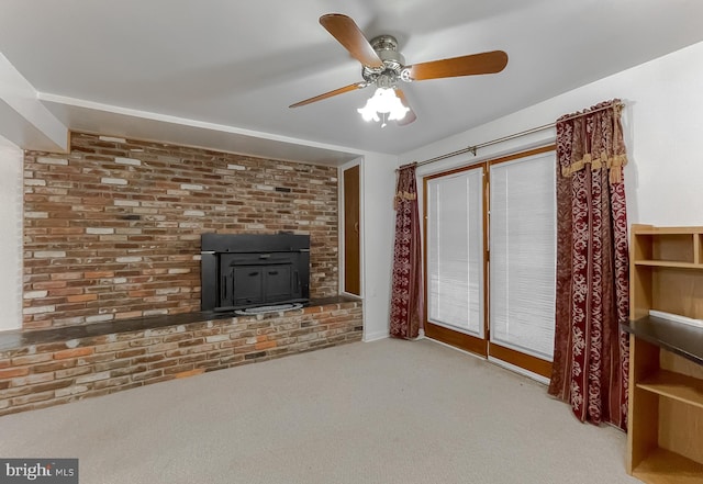 unfurnished living room with carpet flooring, ceiling fan, a wood stove, and brick wall