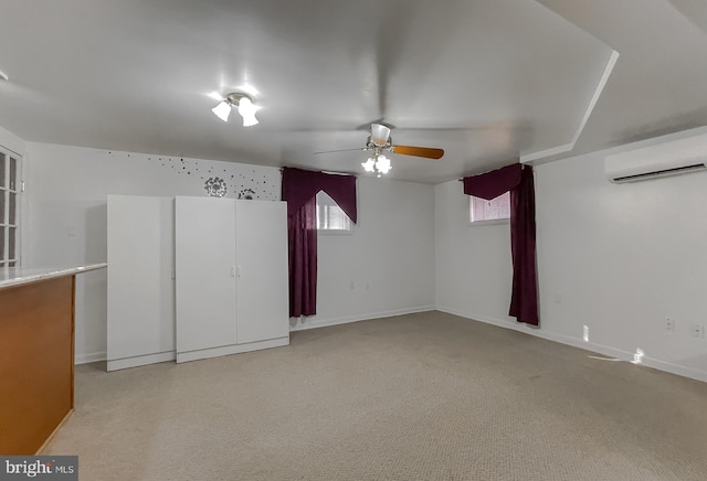 empty room with light colored carpet, an AC wall unit, and ceiling fan