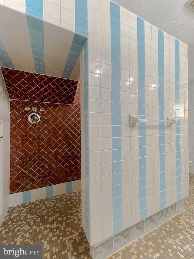 bathroom featuring tile patterned flooring and a tile shower