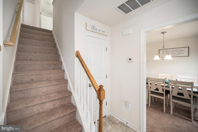 stairs with carpet and a notable chandelier