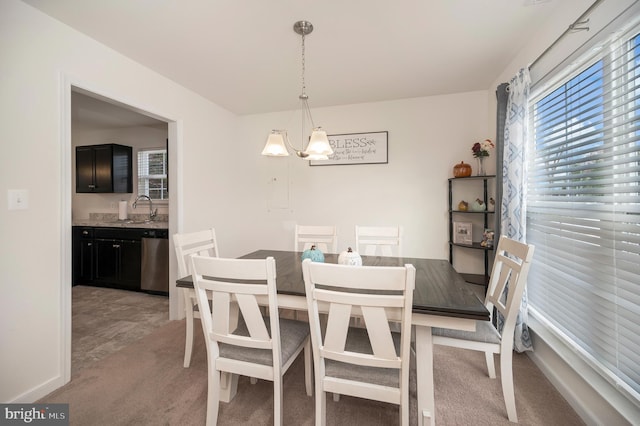 dining space featuring sink, light carpet, and a chandelier