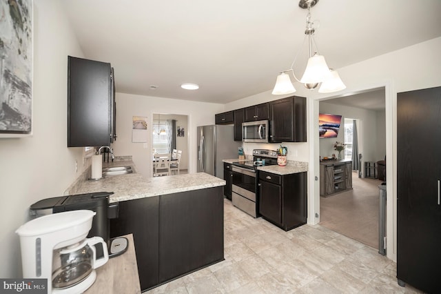 kitchen with appliances with stainless steel finishes, dark brown cabinets, sink, a notable chandelier, and hanging light fixtures