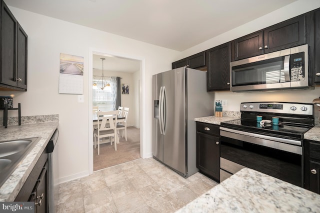 kitchen with appliances with stainless steel finishes, light stone counters, sink, decorative light fixtures, and a chandelier