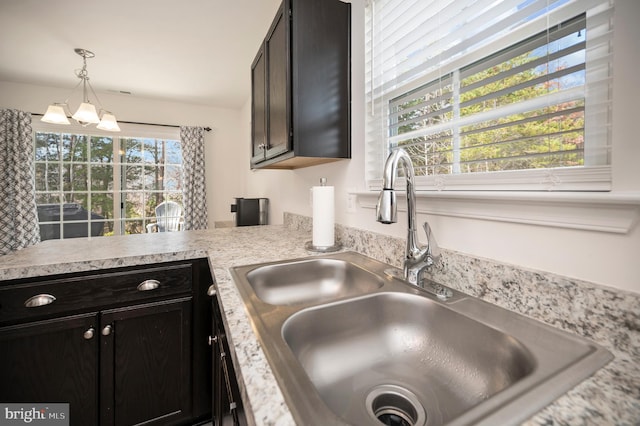 kitchen featuring a wealth of natural light, sink, a chandelier, and decorative light fixtures