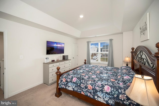 bedroom with a raised ceiling and light colored carpet