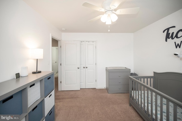 bedroom featuring ceiling fan, light colored carpet, and a crib