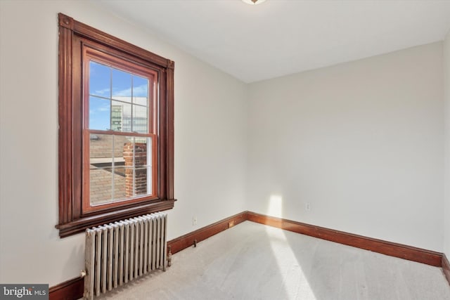 spare room with light colored carpet and radiator heating unit