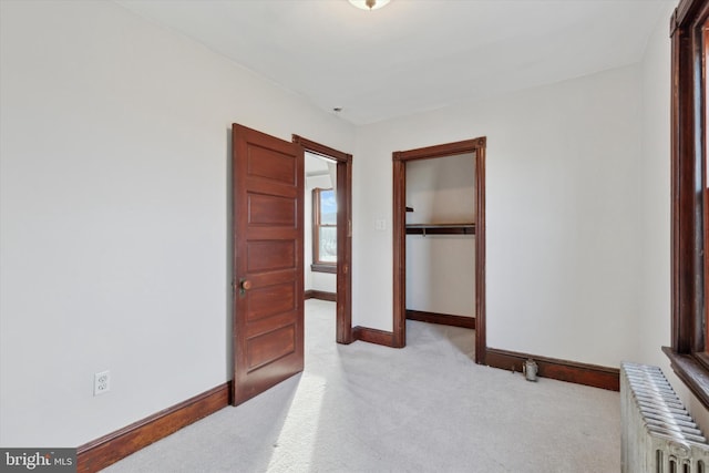 carpeted bedroom with radiator heating unit and a closet