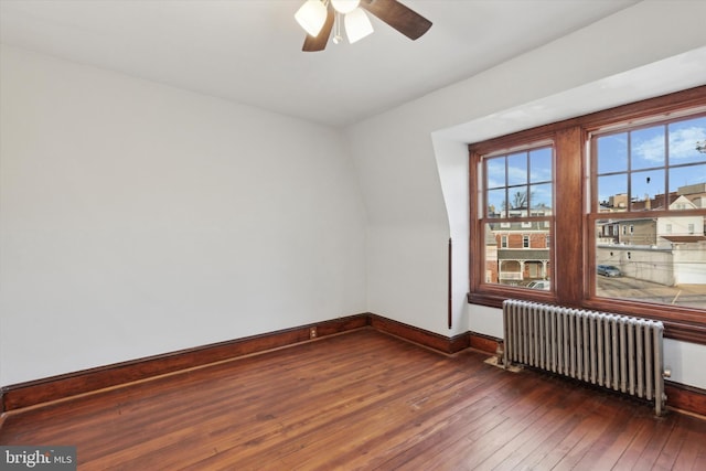 empty room featuring radiator heating unit, dark hardwood / wood-style floors, and ceiling fan