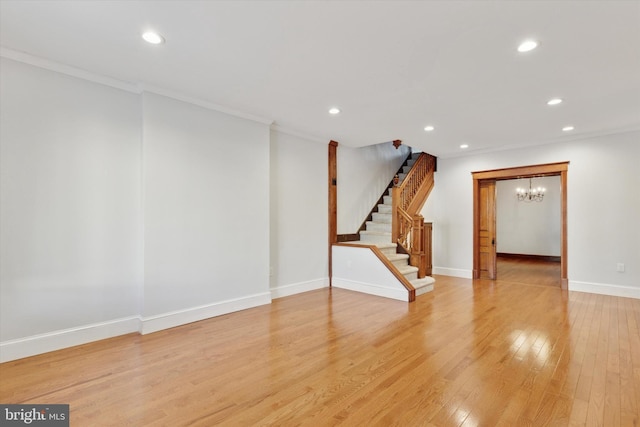 unfurnished room featuring light wood-type flooring, ornamental molding, and an inviting chandelier