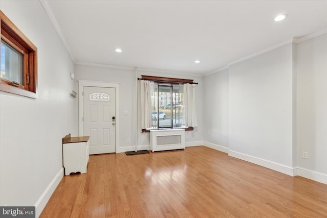 foyer entrance with radiator heating unit, light wood-type flooring, and ornamental molding