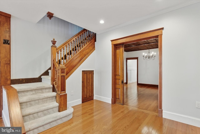 staircase with hardwood / wood-style flooring and a notable chandelier