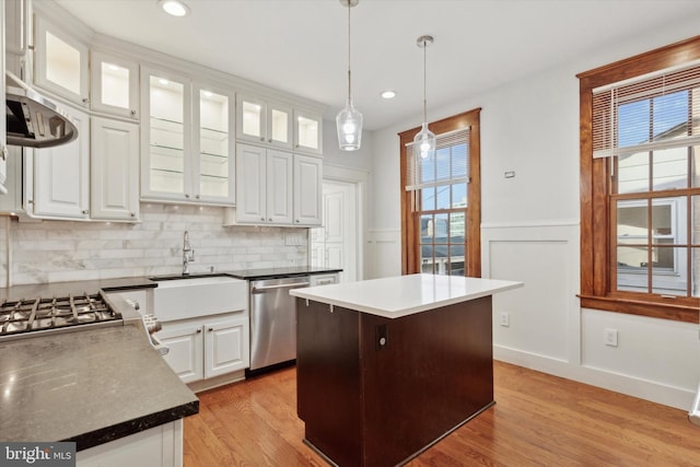 kitchen featuring stainless steel dishwasher, a kitchen island, white cabinetry, and a wealth of natural light