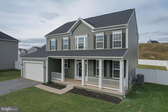 view of front of home with a porch, a front lawn, central AC unit, and a garage